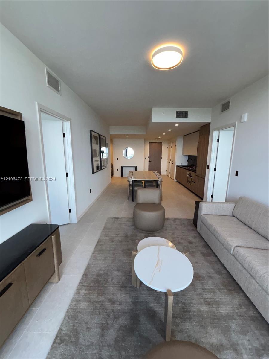 Open-concept interior featuring light-toned flooring, recessed ceiling lighting, flush-mount lighting, and custom cabinetry with integrated kitchen ap