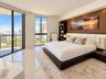 Floor-to-ceiling windows, polished tile flooring, built-in recessed ceiling lighting, and integrated wall-mounted headboard