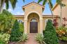 Stucco exterior featuring a covered portico entrance, arched entryway, double-door main entry, and clay tile roof