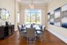 Formal dining area featuring tray ceilings, wood-finish flooring, and a large multi-pane window