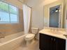 Full bathroom featuring a dark wood-finish vanity with a light-toned countertop, an integrated oval sink, a large wall-mounted mirror, and a tub-showe