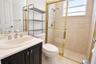 Bathroom featuring a dark wood-finish vanity, integrated oval sink, brass-tone hardware, shower enclosure with glass sliding doors, and tiled wall fin