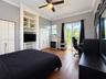 Bedroom featuring wood-finish flooring, custom built-in shelving, double-door closet storage, crown molding, and glass sliding doors