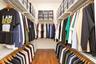 Walk-in closet featuring tiered wire shelving, custom overhead storage compartments, and wood-finish flooring