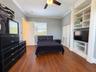 Room featuring custom built-in floor-to-ceiling shelving, wood-finish flooring, crown molding, and a ceiling fan with integrated lighting