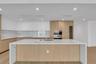 Modern kitchen featuring a waterfall-edge island with stone-finish countertops, two-tone cabinetry, recessed ceiling lighting, a built-in oven, and wo