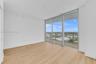 Floor-to-ceiling windows, wood-finish flooring, and access to a private balcony with a metal railing