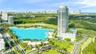 High-rise residential tower featuring an expansive turquoise lagoon, manicured grounds, a podium-level swimming pool, and proximity to coastal terrain