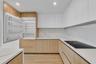 Contemporary kitchen featuring flat-panel wood-finish cabinetry, white matte upper cabinetry, white stone-patterned backsplash, integrated panel-ready