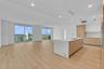 Open-concept interior featuring light wood-finish flooring, a kitchen island with stone-finish waterfall countertop, integrated cabinetry, and floor-t
