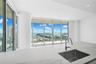 Expansive floor-to-ceiling windows, white countertop with veining, under-mount stainless steel sink, contemporary chrome pull-down faucet, recessed ce