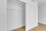 Closet featuring a floor-to-ceiling sliding door, integrated wire shelving, and wood-finish flooring
