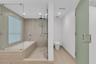 Bathroom featuring wood-finish tile wall and floor surfaces, a soaking tub with a glass partition, a walk-in shower with a dual-head fixture, and a fr