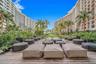 Expansive wooden deck featuring mature palm trees, curated tropical landscaping, and large-scale residential architecture