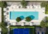 Rectangular swimming pool with stone-surround decking, enclosed tennis court, integrated metal pergolas, and established perimeter landscaping