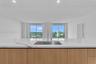 Kitchen island with waterfall-edge stone countertop, undermount stainless steel rectangular sink, tall arching faucet, wood-finish cabinetry, and floo