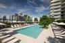 Swimming pool featuring a large concrete deck, integrated mature landscaping, and an expansive cityscape backdrop