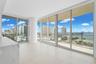Floor-to-ceiling windows, white tile flooring, built-in counter with marbled finish, and roller shades