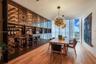 Built-in wine storage cabinetry with glass-front doors, wood-finish flooring, full-height windows, and a contemporary chandelier