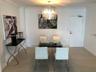 Neutral-toned tile flooring, drum-style chandelier with metallic finish, crown molding, and solid-core entry door
