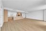 Open-concept interior featuring wood-finish flooring, recessed lighting, and a kitchen equipped with flat-panel wood cabinetry, white stone-surface co