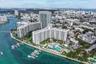 Aerial perspective of a waterfront residential complex featuring a swimming pool, boat slips, and coastal landscaping
