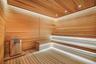Wood-paneled sauna featuring tiered wooden benches and an integrated stainless steel heater