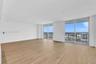 Open-concept living space featuring wood-finish flooring, floor-to-ceiling glass sliding doors, and exterior balcony access