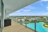 Covered balcony featuring wood-finish tile flooring, a built-in outdoor grill station with stone-finish cladding, and a glass panel railing