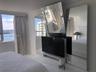 Floor-to-ceiling windows, white tile flooring, built-in white media console, and floor-to-ceiling mirrored wall panels