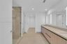 Floating wood-finish vanity with dual integrated sinks, light-toned countertop, floor-to-ceiling glass enclosed shower with integrated niche, and full