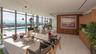 Expansive floor-to-ceiling windows, private outdoor pool, light-toned tile flooring, wood-paneled accent wall, and built-in wood-finish cabinetry