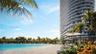 High-rise residential tower featuring curved glass balconies, situated along a private lagoon with a sandy beach and mature palm landscaping