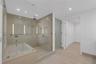 Glass-enclosed wet room featuring a deep soaking tub, walk-in shower with stone-tile surround, integrated recessed shelving, and wood-finish flooring