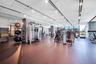 Expansive fitness center with track lighting, multiple exercise machines, and extensive window walls