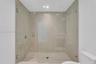 Walk-in shower featuring floor-to-ceiling large-format tile, frameless glass enclosure, recessed lighting, and chrome shower fixtures