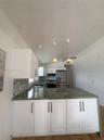 Kitchen featuring white shaker-style cabinetry, solid-surface countertops with waterfall edge, geometric tile backsplash, stainless steel appliances, 