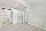 Interior space featuring light-toned wood-finish flooring, white built-in cabinetry, a sliding barn-style door, and a wall-mounted climate control uni