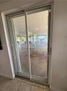 Sliding glass door opening to a covered ground-level patio with structural support columns and tile flooring