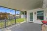 Covered wood-deck porch featuring a railing, full-glass exterior door, and stucco wall finish