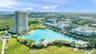 High-rise residential structure featuring an expansive crystalline lagoon, landscaped grounds, palm tree accents, and paved pedestrian pathways
