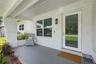 Covered front porch featuring painted brick exterior, concrete flooring, exterior wall-mounted lantern light fixture, and a full-light glass panel ent