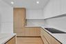 Modern kitchen featuring flat-panel wood-finish cabinetry, floor-to-ceiling refrigerator paneling, white solid-surface countertops, stone-patterned ba