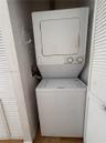 Stacked white washer and dryer unit enclosed by bi-fold louvered doors