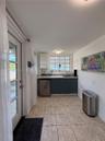 Kitchenette featuring dark cabinetry, solid-surface countertops, tile flooring, and a multi-pane window