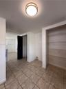 Neutral-toned ceramic tile flooring, built-in wire shelving, and a flush-mount circular ceiling fixture