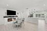 Open-concept interior featuring shiplap fireplace surround, electric fireplace insert, wood-finish flooring, kitchen island with pendant lighting, and