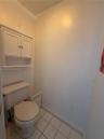 White wall-mounted cabinetry featuring shaker-style doors, an open lower shelf, and ceramic tile flooring