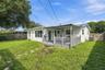 Rear exterior featuring a covered wood deck with railing, stucco siding, and a fenced backyard