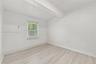 Interior room featuring wood-finish flooring, a single-pane window with adjustable blinds, and smooth-finish walls
